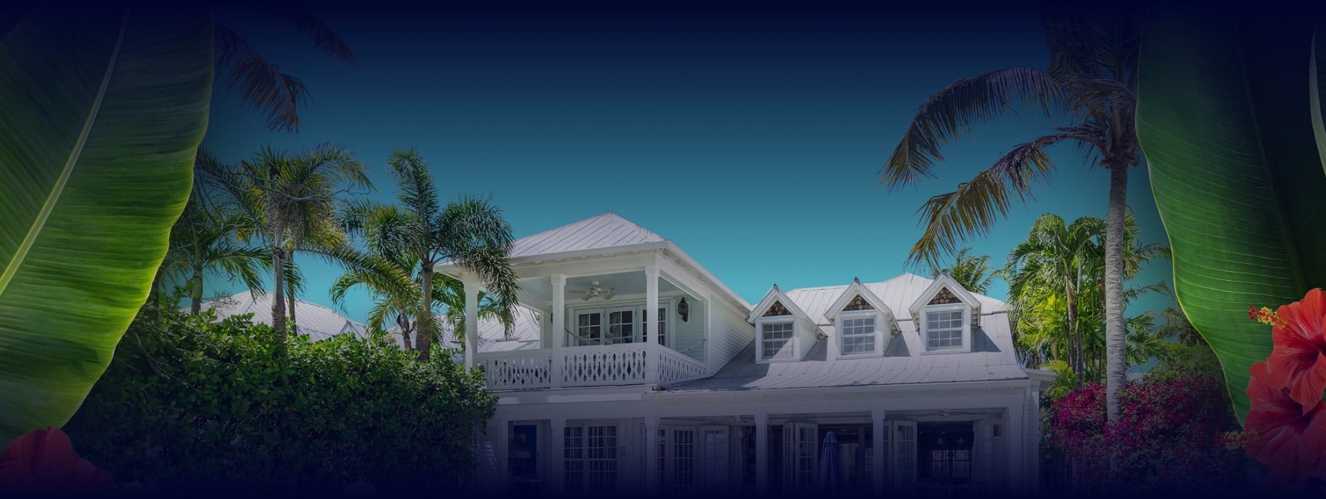 Background image for Vacation Homes Of Key West's case study showing a tropical white house with palm trees and flowers