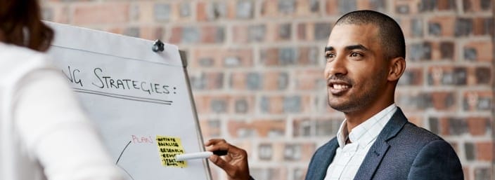 Man presenting marketing strategies on board