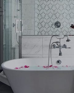 Modern bathroom with a freestanding bathtub, chrome fixtures, tiled walls, and a glass shower, showcasing residential plumbing