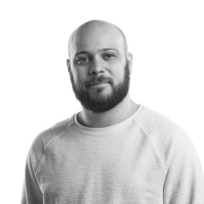 Home Page - NEW 296 Black-and-white portrait of a bearded man in a light crewneck sweater against a plain white background